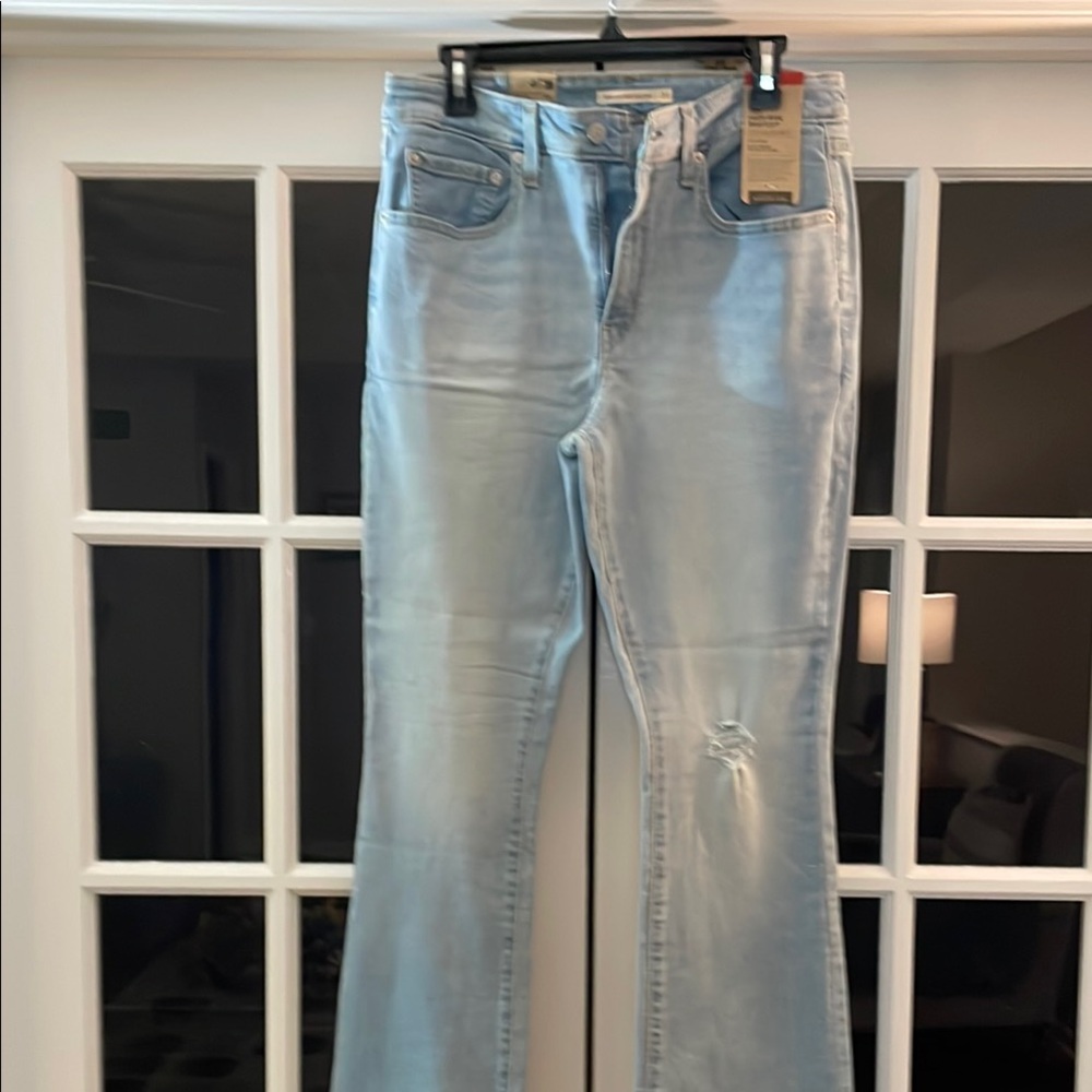 Never worn Levi 725 high rise boot cut jeans with distressed knee. 31x32.